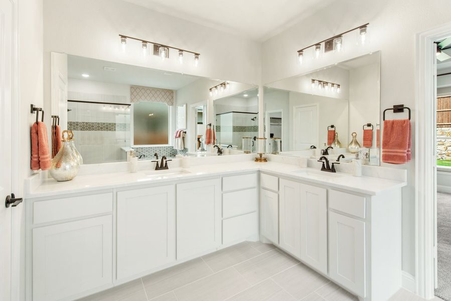 Master bathroom with dual vanities, white cabinets, large mirrors, and a walk-in shower visible in the background.