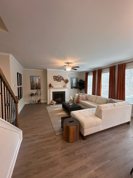 A cozy living room featuring a large sectional, warm wood floors, and a stylish fireplace with modern decor accents.