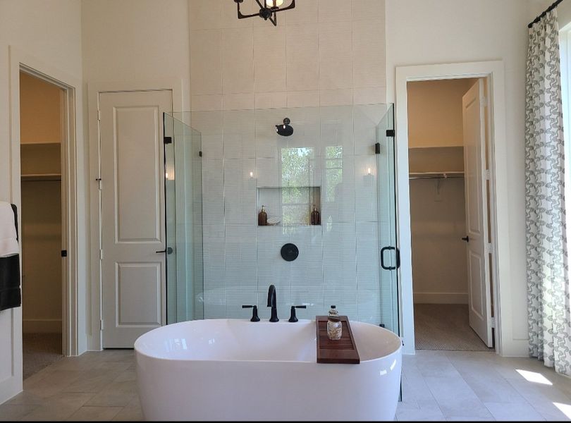 A luxurious bathroom with a freestanding tub, glass shower, and elegant, neutral-toned walls.