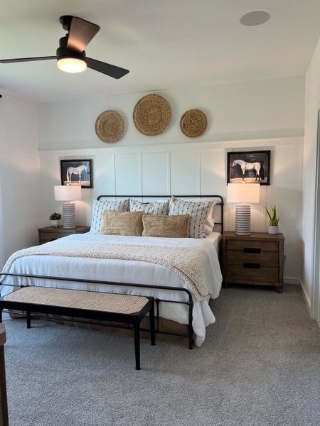 A cozy bedroom featuring a plush bed, stylish decor, wicker accents, and modern ceiling fan for a serene ambiance.