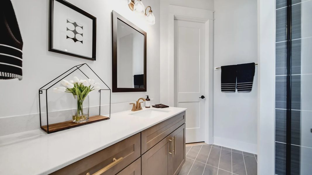 Experience luxury with a dark wood vanity and quartz counter in Shelton Square’s refined bathroom.