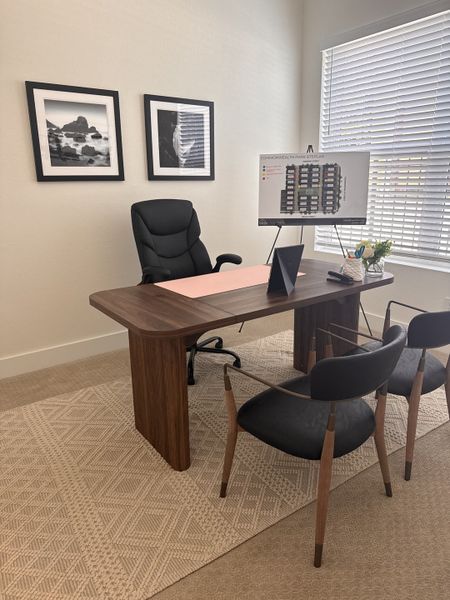 A modern office with a sleek wooden desk, cozy chairs, and elegant black-and-white wall art.