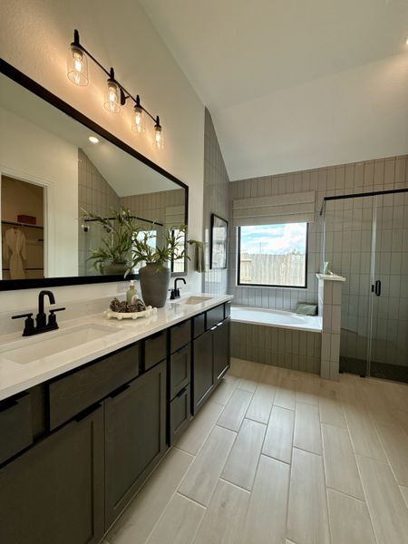 A chic bathroom featuring dual sinks, a sleek black vanity, large mirror, and natural light streaming through a spacious window. A chic bathroom featuring dual sinks, a sleek black vanity, large mirror, and natural light streaming through a spacious window.