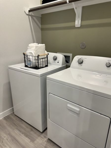 Modern laundry room with sleek appliances, stylish shelving, and elegant flooring for efficient home living.