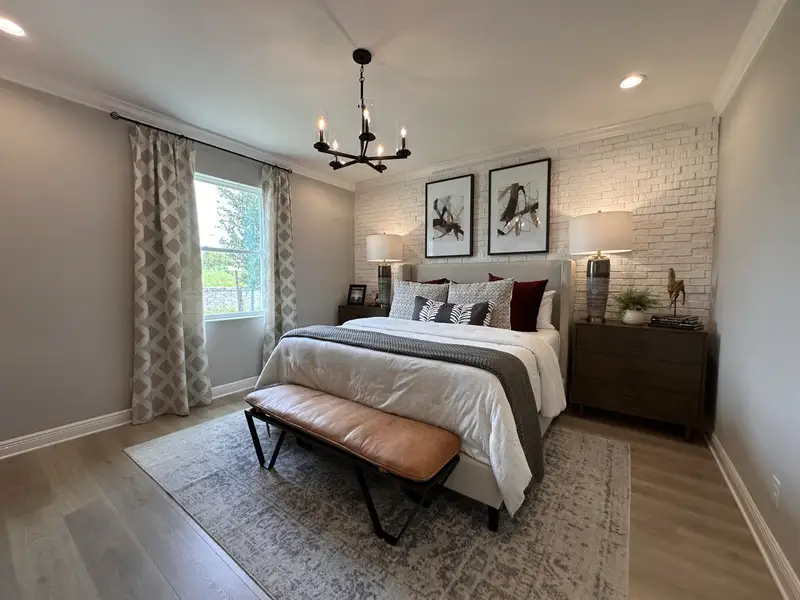 A cozy bedroom with a textured white brick wall, elegant lighting, and plush bedding, creating a serene and inviting atmosphere.
