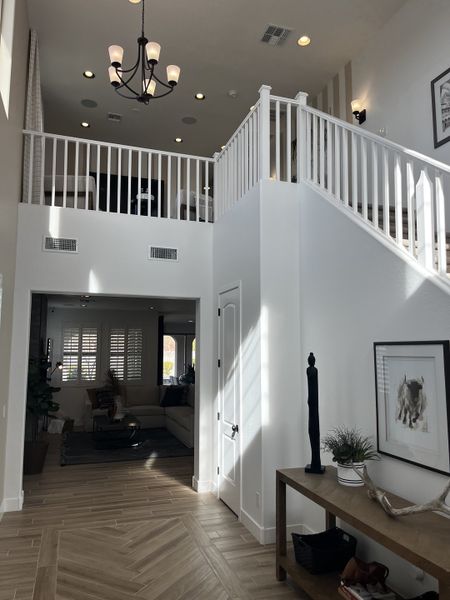 A bright foyer with a high ceiling, a loft view, and stylish decor.