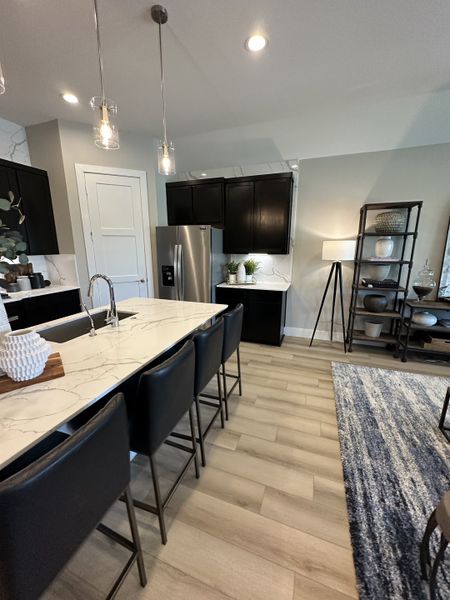 A modern kitchen with a marble island, sleek black cabinets, and stylish pendant lighting.