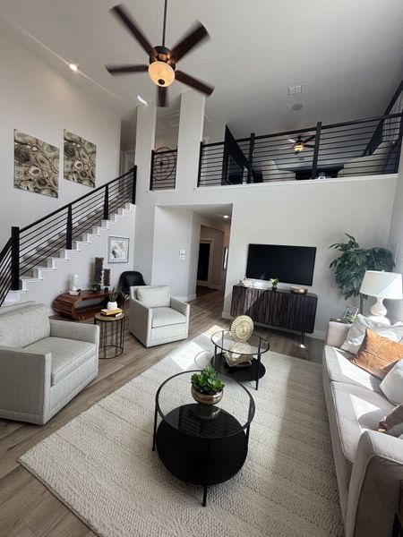 A bright, inviting living room with high ceilings, soft neutral furnishings, and a stylish modern railing leading upstairs. A bright, inviting living room with high ceilings, soft neutral furnishings, and a stylish modern railing leading upstairs.