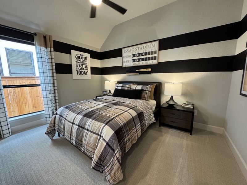 A cozy bedroom with plaid bedding, bold black stripe accent wall, and ample natural light from large windows.