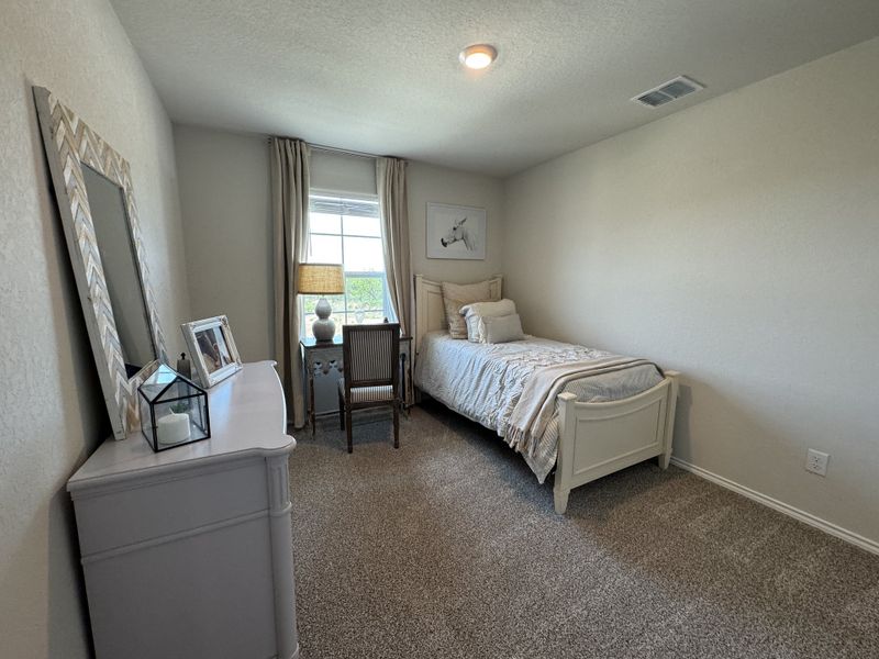 A cozy bedroom featuring a single bed, neutral tones, and a window with natural light, perfect for relaxation.
