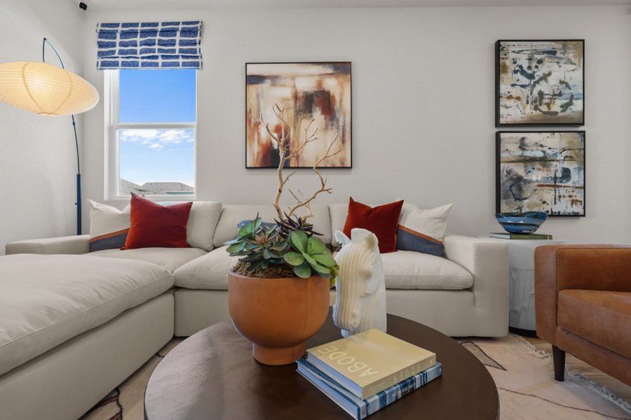 A living room with a white couch and a plant in a pot.