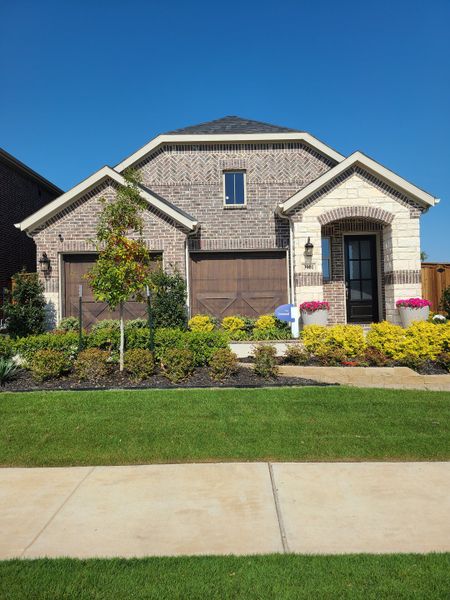 A charming brick home with lush landscaping in Spiritas Ranch by Mattamy Homes (Little Elm, TX).
