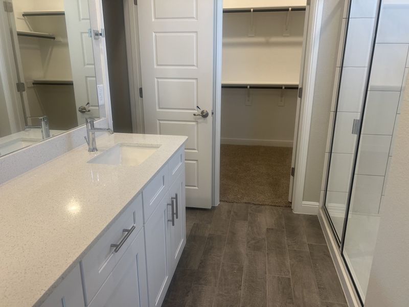 A modern bathroom with sleek white cabinetry, quartz countertops, a spacious shower, and a walk-in closet. A modern bathroom with sleek white cabinetry, quartz countertops, a spacious shower, and a walk-in closet.