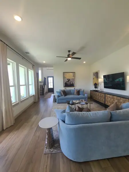 A spacious living room featuring cozy blue sofas, wooden flooring, and modern art for a stylish, comfortable setting.