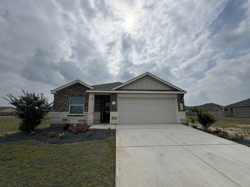 A charming brick home with a spacious driveway and landscaped yard in Parkside: Watermill Collection by Lennar (New Braunfels, TX).