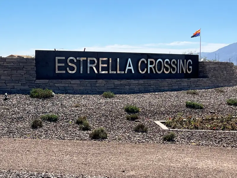 A welcoming entrance to Estates at Estrella Crossing by Ashton Woods, featuring a stone sign in Phoenix, AZ.