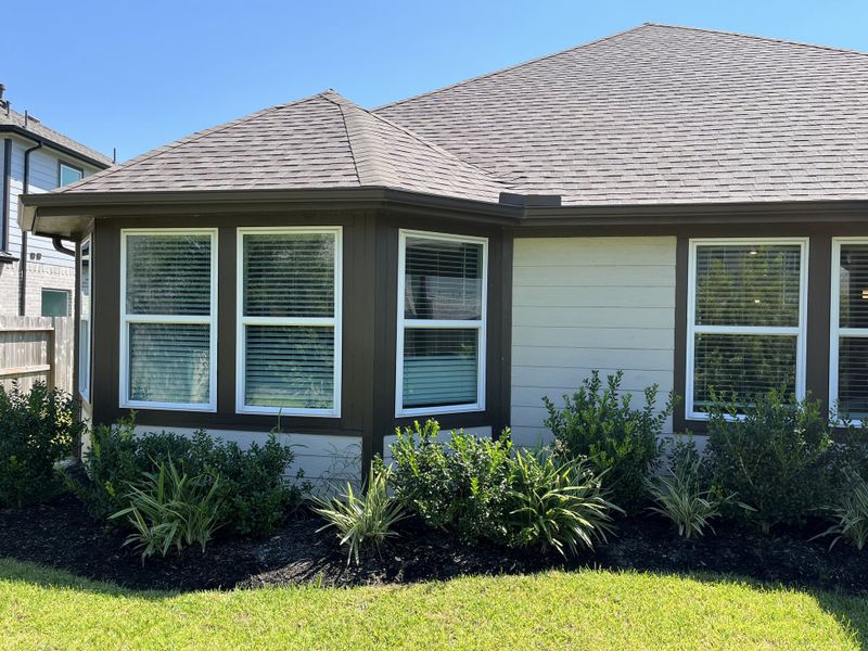 Charming white siding home with lush landscaping in Massey Oaks - Estate Series by Meritage Homes (Pearland, TX).