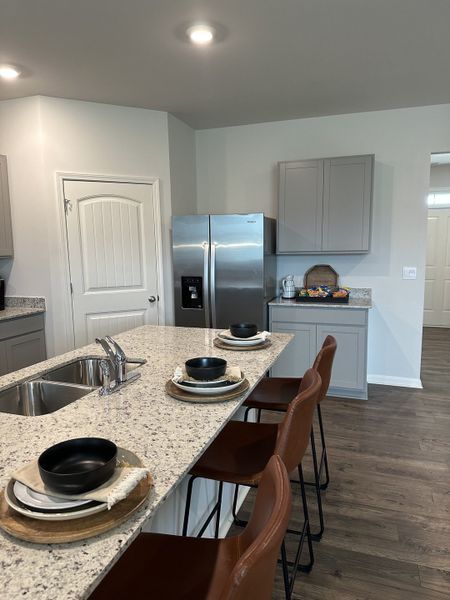 A modern kitchen with granite countertops, sleek appliances, and stylish bar seating.