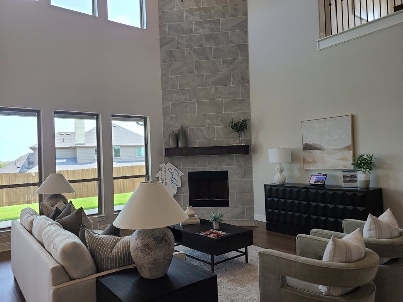 A contemporary living area with tall windows, a stone fireplace, and elegant furnishings, exuding warmth and style.