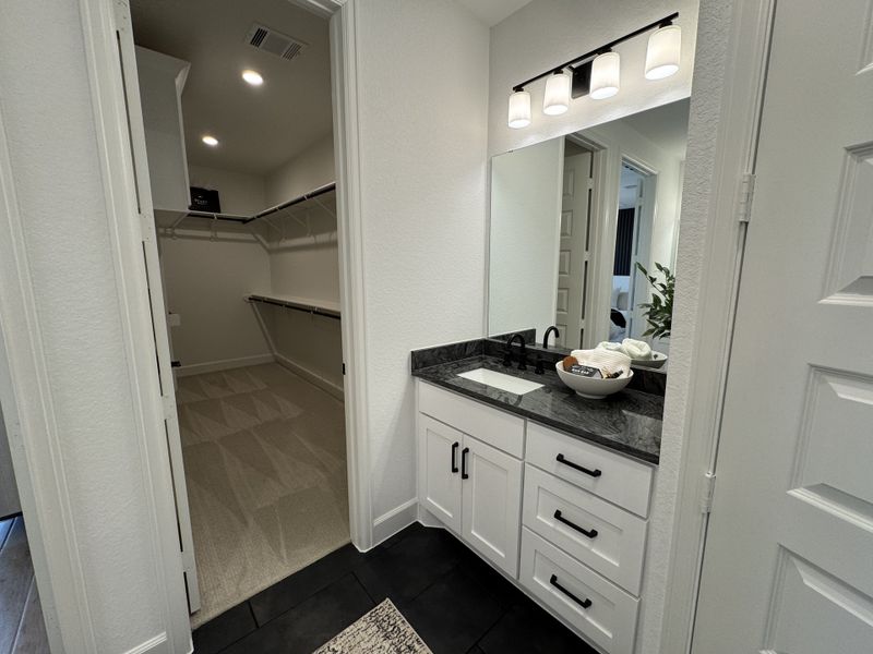 A modern vanity with black fixtures and a spacious walk-in closet featuring ample shelving and storage space.
