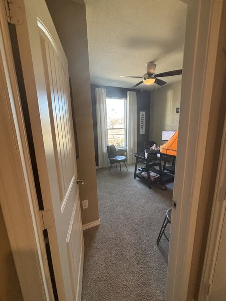 A cozy home office with neutral walls, a ceiling fan, and natural light streaming through large windows. A cozy home office with neutral walls, a ceiling fan, and natural light streaming through large windows.