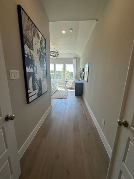A sleek hallway leading to a bright bedroom with modern art, large windows, and stylish light fixtures. A sleek hallway leading to a bright bedroom with modern art, large windows, and stylish light fixtures.