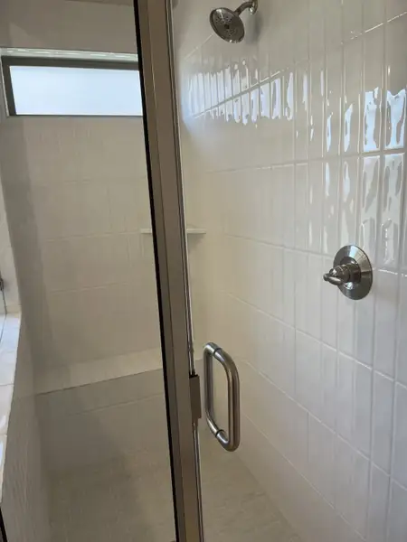 A modern shower with sleek glass doors, white tiles, and a chrome showerhead for a clean, contemporary look. A modern shower with sleek glass doors, white tiles, and a chrome showerhead for a clean, contemporary look.