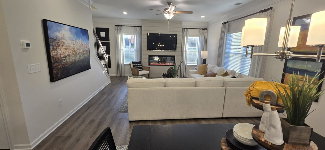 A cozy living room with a sectional sofa, modern fireplace, and elegant decor, complemented by warm lighting and wooden floors.