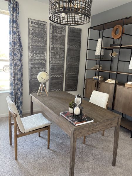 A chic home office with a wooden desk, stylish shelving, and decorative wall panels, featuring a modern globe and hourglass.