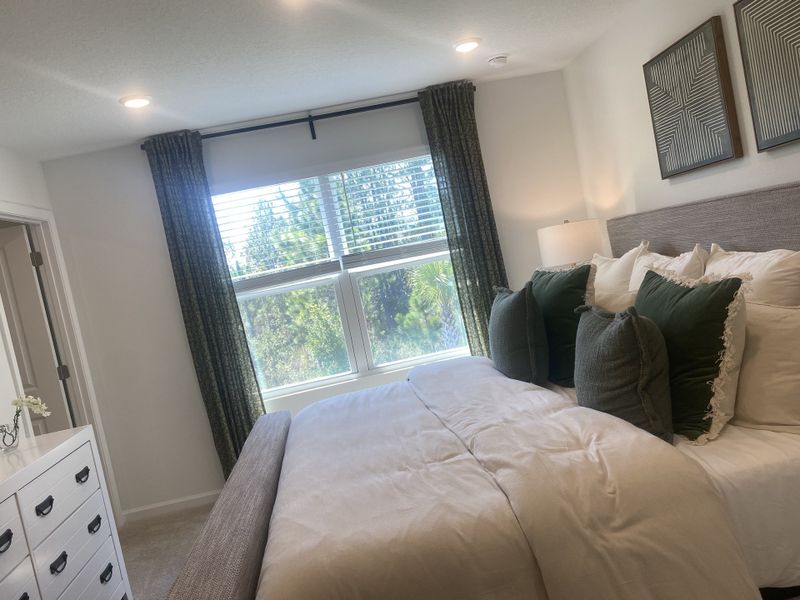 A cozy bedroom with elegant décor, plush bedding, and large windows framed by dark curtains.