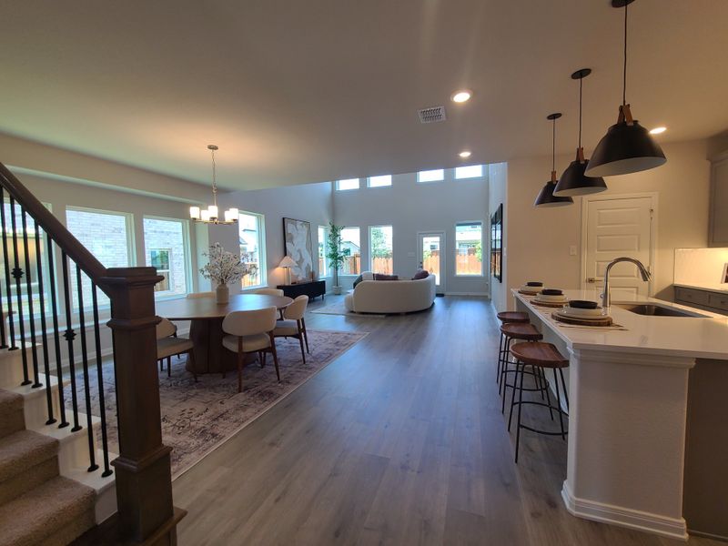 An inviting open-concept living area featuring a sleek kitchen island, chic lighting, and an elegant dining space.