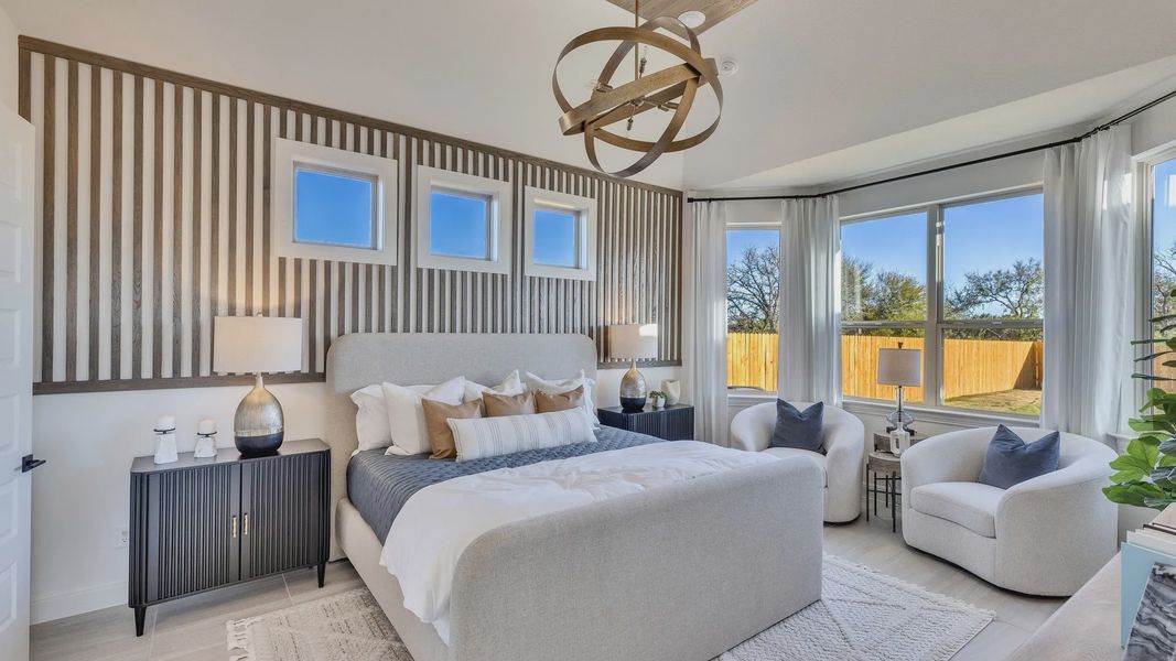 Experience sophistication in this Creeks Crossing bedroom featuring a wood accent wall and stunning lighting.