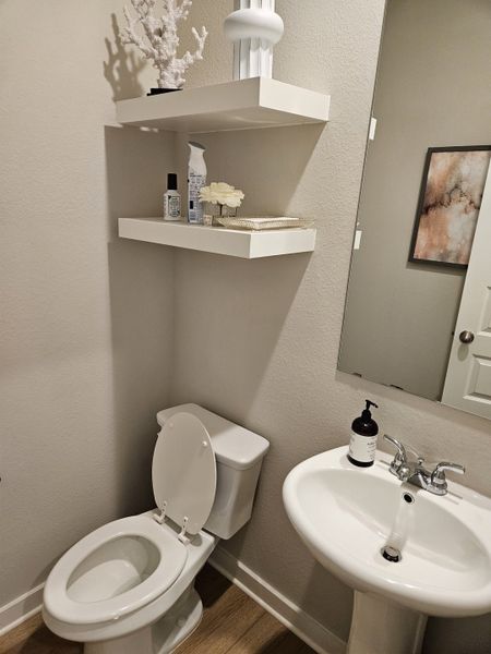 A compact bathroom features floating shelves, modern decor, a sleek pedestal sink, and a practical layout. A compact bathroom features floating shelves, modern decor, a sleek pedestal sink, and a practical layout.