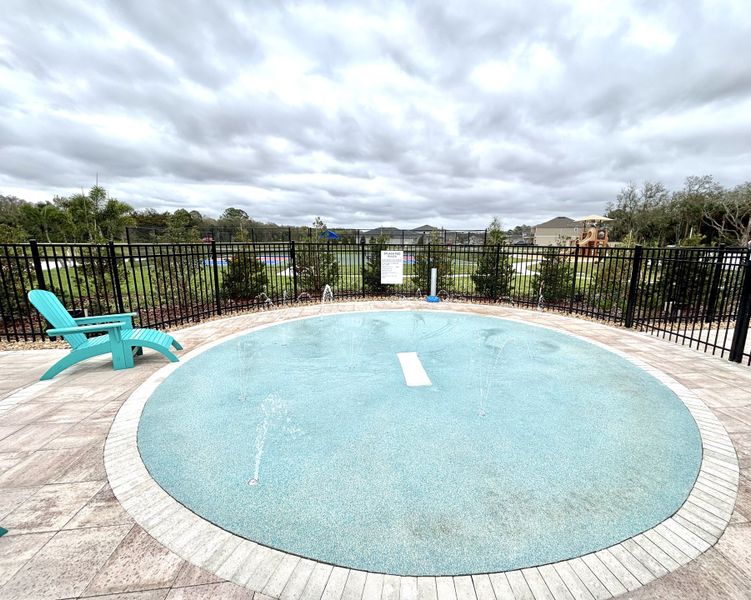A relaxing circular splash pad with a turquoise chair in Naples Village at Verona I by KB Home (Titusville, FL).