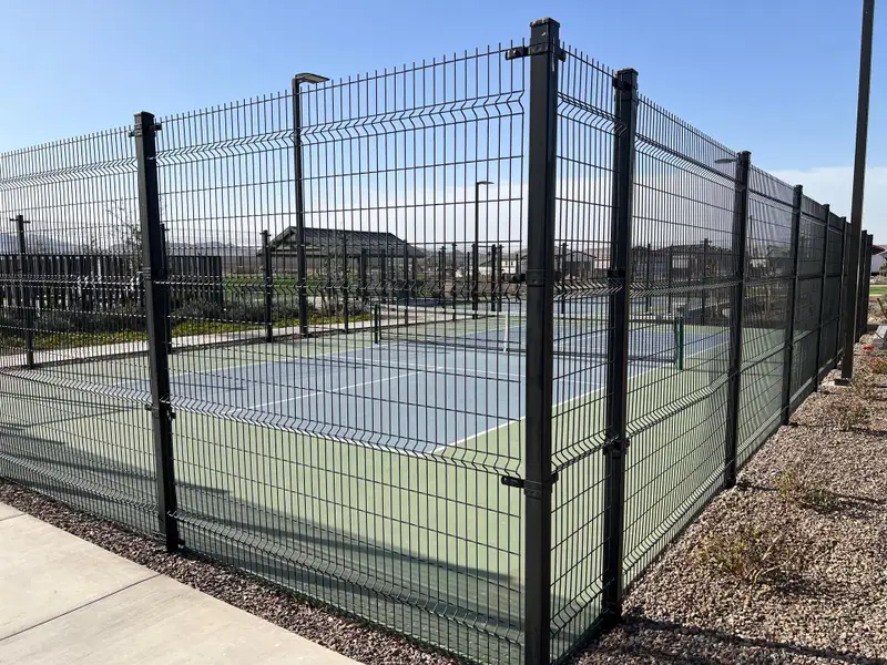 A well-maintained tennis court surrounded by a fence in Avion: Arbor by Lennar, Goodyear, AZ. Perfect for sports enthusiasts.