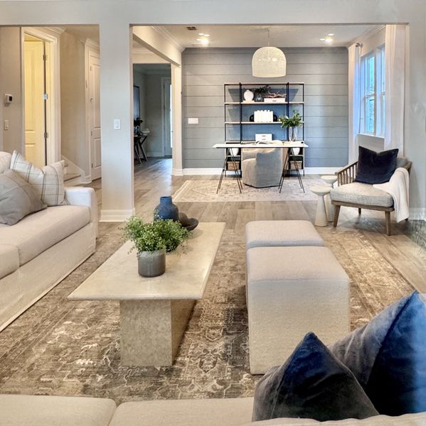 A cozy living room with plush seating, a stone coffee table, and a chic workspace featuring a stylish desk and shelves.