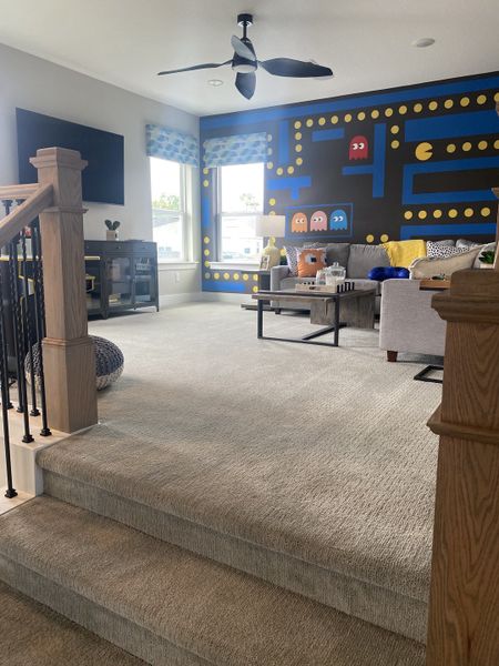 A cozy loft with playful, vibrant wall art, plush seating, and modern decor, ideal for relaxation and entertainment.