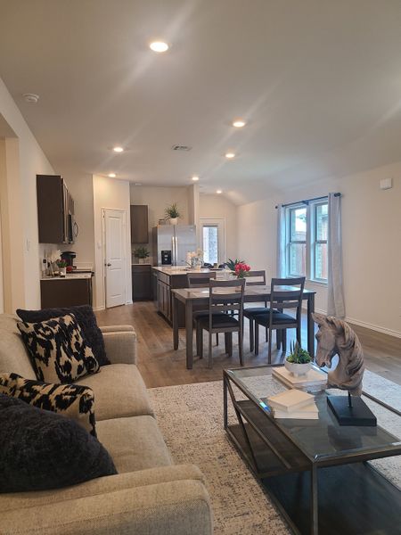 A cozy living area with a beige sofa, modern dining set, and sleek kitchen, featuring warm wood floors and bright lighting. A cozy living area with a beige sofa, modern dining set, and sleek kitchen, featuring warm wood floors and bright lighting.
