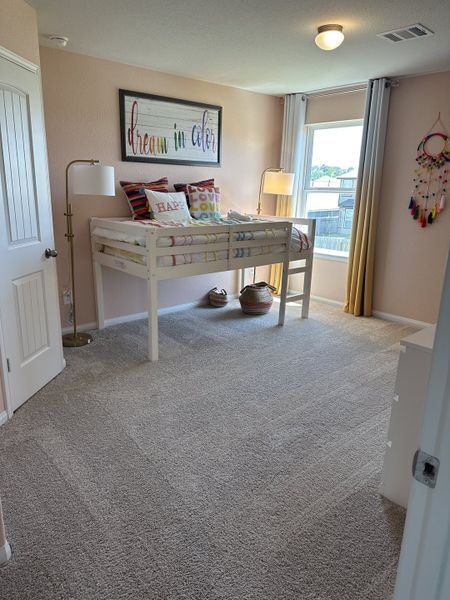 A cozy kids' room with a loft bed, colorful pillows, soft carpet, and cheerful decor. Bright and inviting atmosphere.