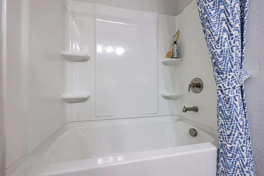 A bathroom with a bathtub and shower curtain. A bathroom with a bathtub and shower curtain.