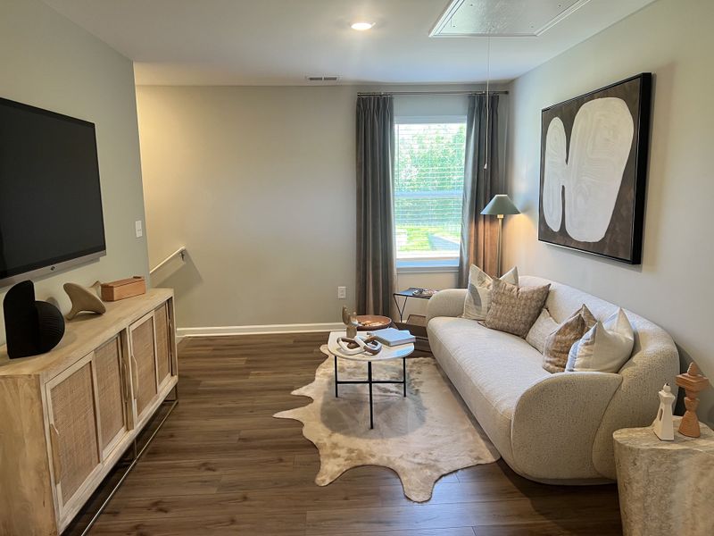 A cozy living room featuring a plush curved sofa, abstract art, and wooden furnishings, perfect for relaxation.