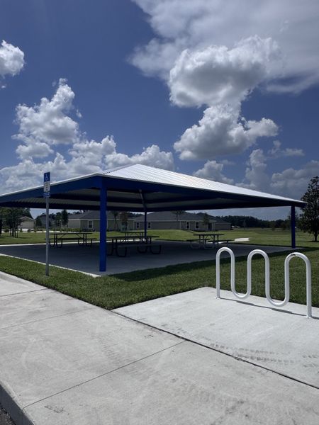 A modern park pavilion with picnic tables and bike racks in Holstein Crossing: Holstein Crossing 50s by Lennar (Green Cove Springs, FL).