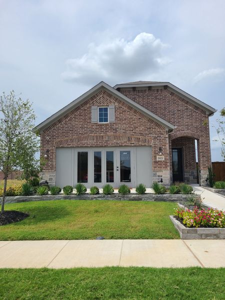 A beautiful brick home with a manicured lawn in Creekview Fossil Ridge by Ashton Woods (Pilot Point, TX).