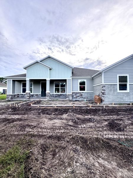 A modern blue and stone-clad home in Jeremy’s Drive by Maronda Homes, Green Cove Springs, FL, awaiting landscaping.