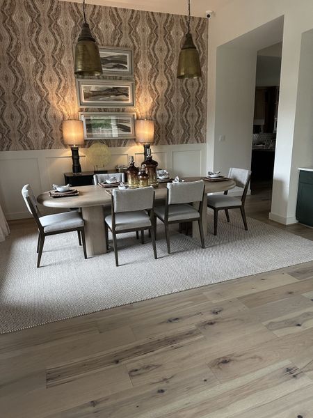 A chic dining area with wood floors, patterned wallpaper, and elegant lighting, perfect for gatherings and cozy dinners.