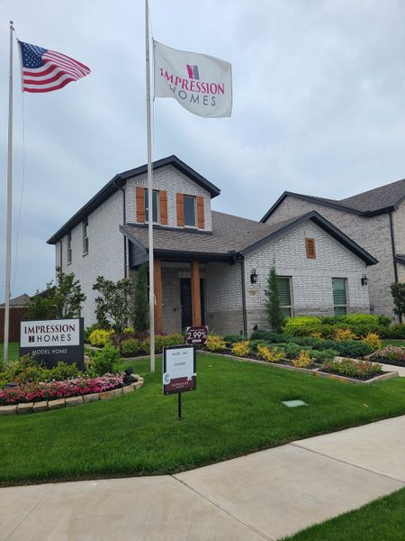 Charming brick home with wooden shutters and lush landscaping in Bryant Farms by Impression Homes (Melissa, TX).