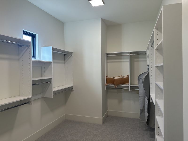 A spacious walk-in closet featuring built-in shelves and bright natural light, perfect for organized living.