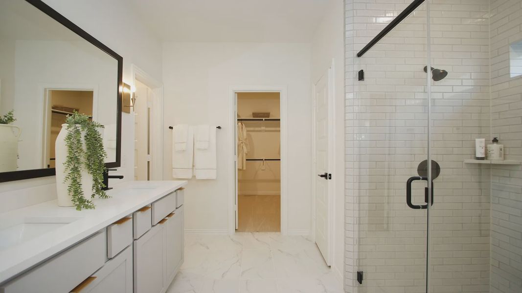 Marble tiles and frameless glass shower enhance this bathroom's elegance in The Woodlands Hills.