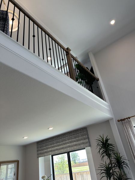 A modern living area featuring high ceilings, a sleek iron railing, and large windows for ample natural light. A modern living area featuring high ceilings, a sleek iron railing, and large windows for ample natural light.