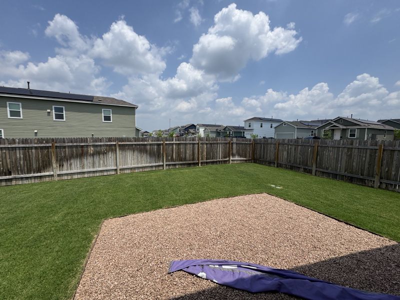 A spacious backyard with a wooden fence and gravel patio area in Sunset Oaks: Wellton Collection by Lennar (Maxwell, TX). A spacious backyard with a wooden fence and gravel patio area in Sunset Oaks: Wellton Collection by Lennar (Maxwell, TX).